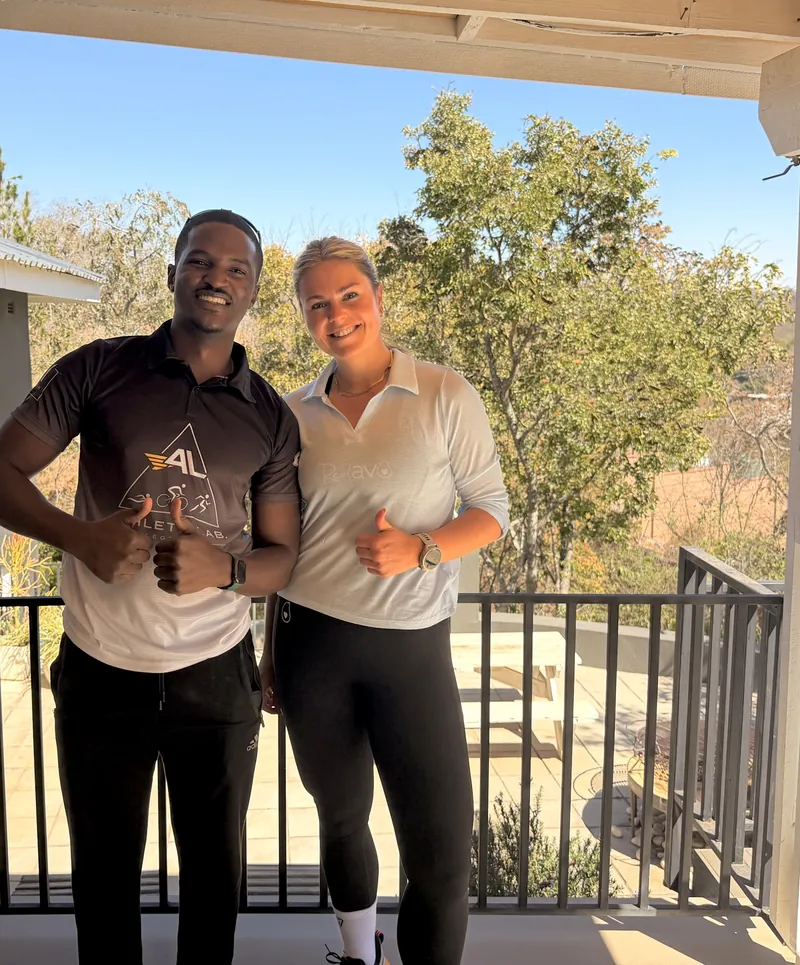 Two people smiling and giving a thumbs-up, one wearing an Athlete Lab shirt