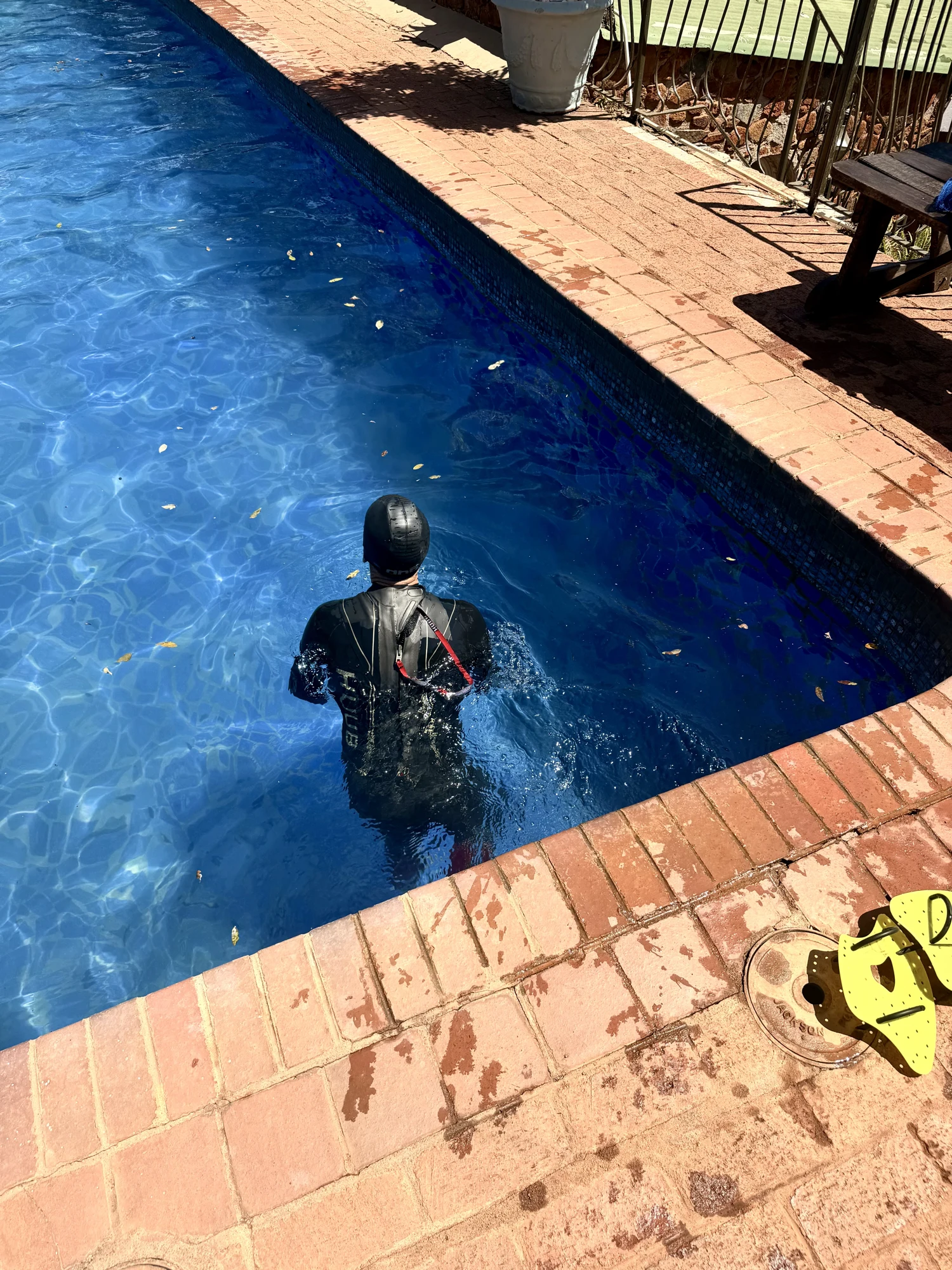 A swimmer wearing a black wetsuit in an outdoor swimming pool